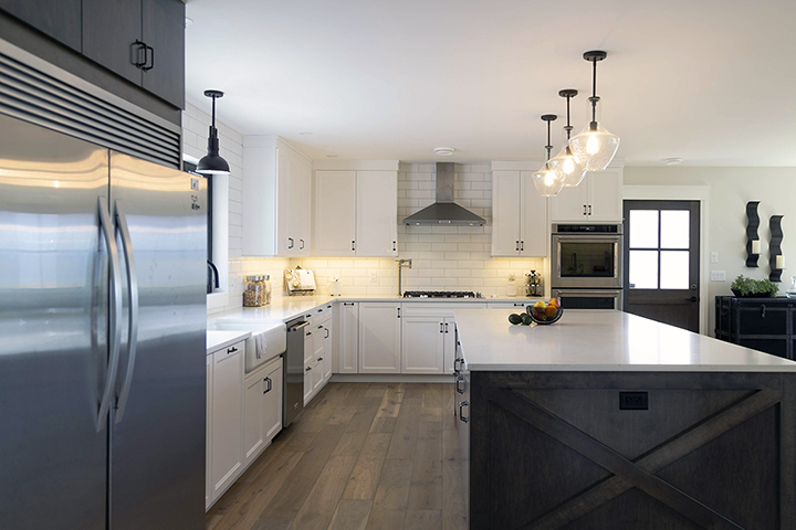 Modern Farmhouse Renovation in a kitchen with a large island, sub-zero refrigerator, farmer sink and elegant contemporary lighting. Design by MATERIA Interior Design Studio in British Columbia.