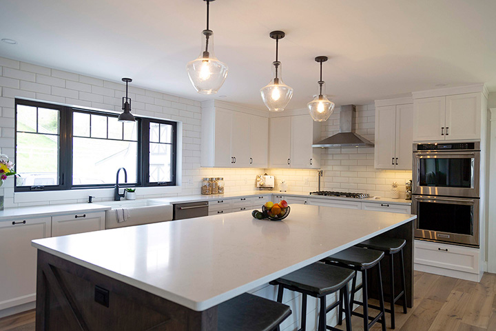 Modern Farmhouse Renovation in a kitchen with a large island, sub-zero refrigerator, farmer sink and Del Mar Alta Vista hardwood floors. Design by MATERIA Interior Design Studio in British Columbia. Modern Farmhouse kitchen with Del Mar Alta Vista hardwood floors.